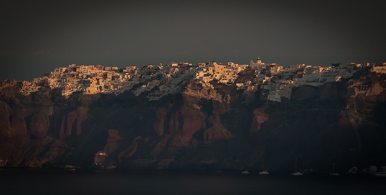 Sonnenaufgang über den Häusern von Oia am Calderarand von Santorini, das erste Licht auf den weißen Fassaden