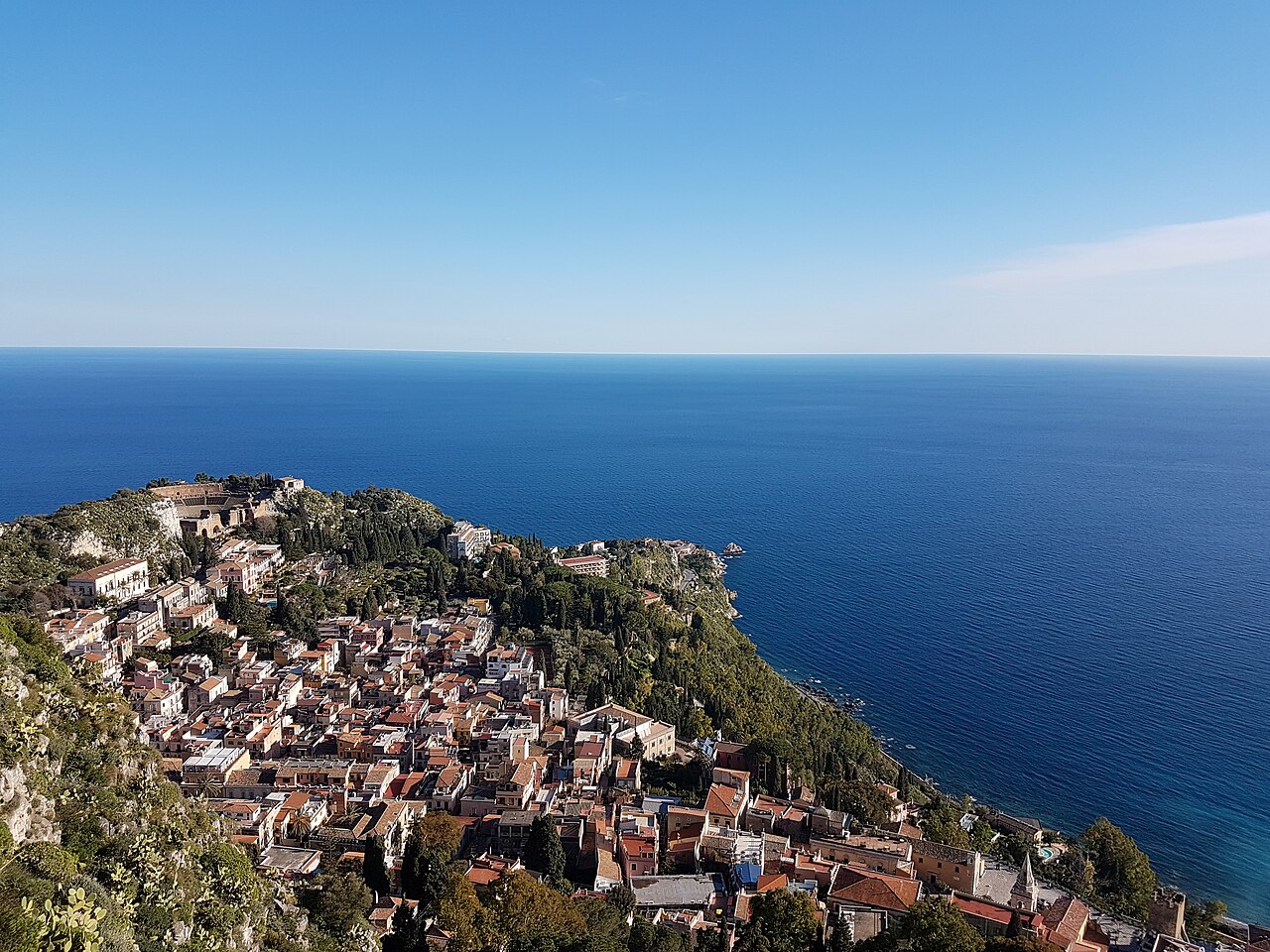 Blick von oben auf Taormina an der sizilianischen Steilküste und das tiefblaue Mittelmeer